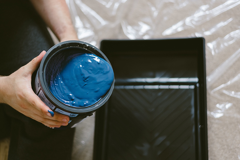 A painter holding a bucket of blue wall paint
